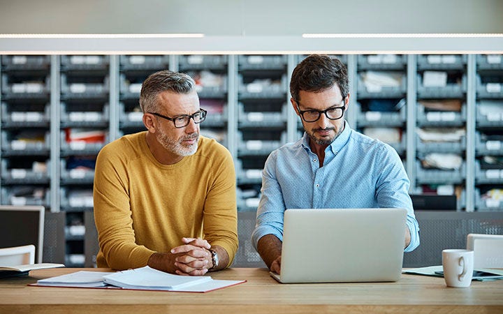 Hombres mirando un computador en una oficina Hombres mirando un computador en una oficina