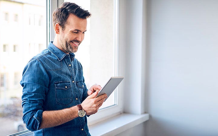 Hombre sonriendo mirando tablet Hombre sonriendo mirando tablet