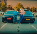 Dos hombres posando frentes a sus vehiculos colectivos