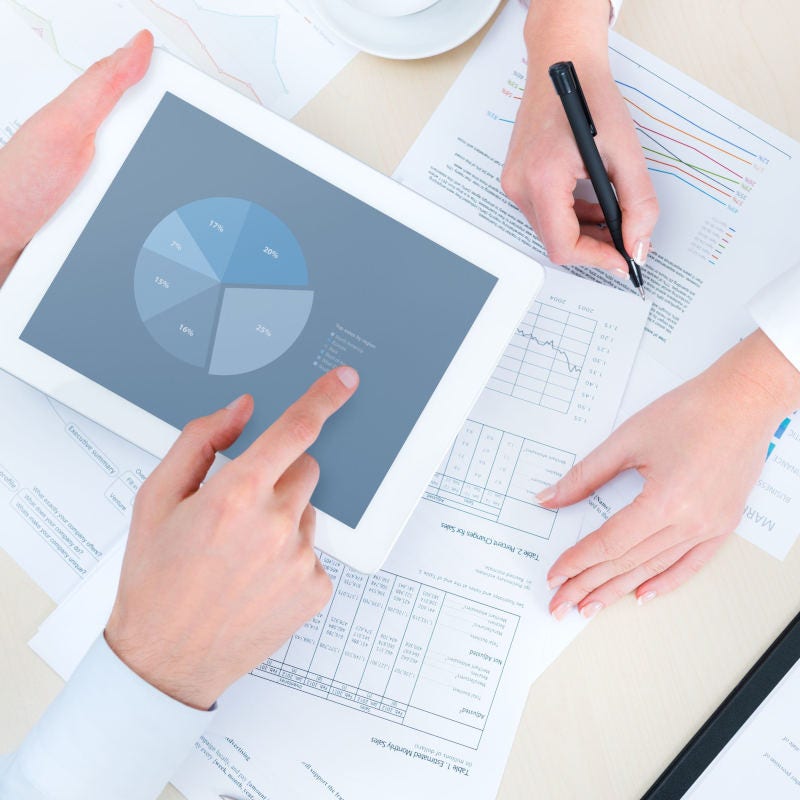 Manos revisando informes y gráfico en tablet Manos revisando informes y gráfico en tablet