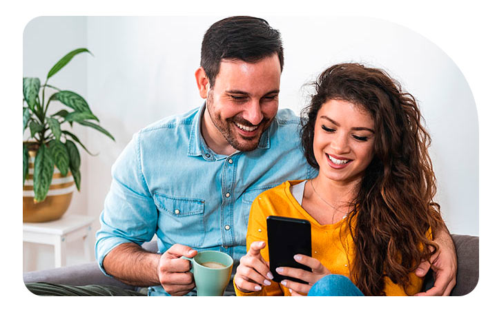 Pareja sonriendo mirando pantalla de celular Pareja sonriendo mirando pantalla de celular