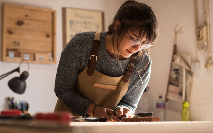 Mujer trabajando en madera sobre una mesa