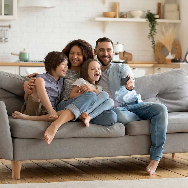 Familia sonriendo tomándose una fotografía sentados en un sofá