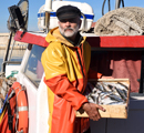 Pescador saliendo de su bote con una caja de pescados