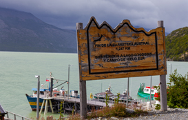 Cartel de madera frente a un lago indicando fin de la Carretera Austral