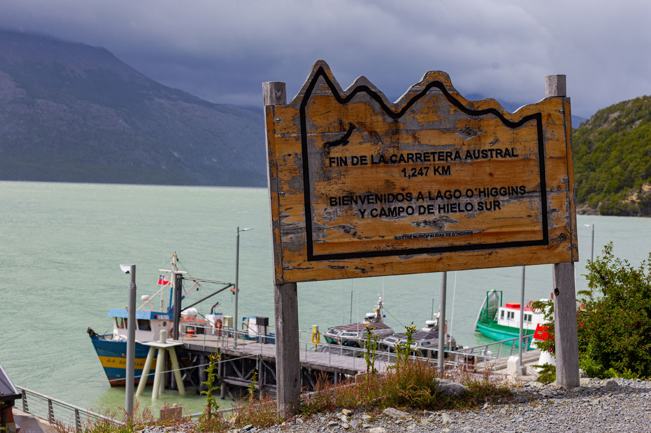 Cartel de madera frente a un lago indicando fin de la Carretera Austral