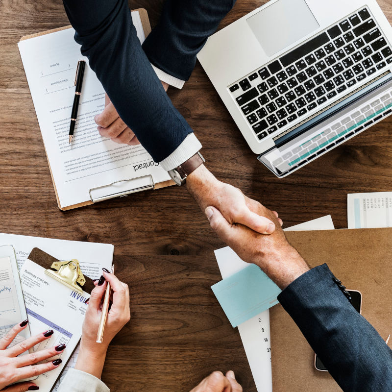 Manos estrechadas con equipos e informes alrededor